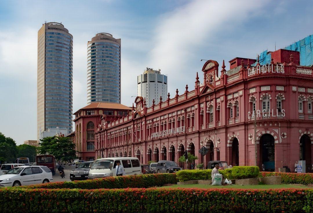 View of a historic red building with modern skyscrapers in the background under a blue sky.